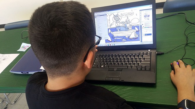 A student in the comic book class editing and coloring his comic book on the computer.