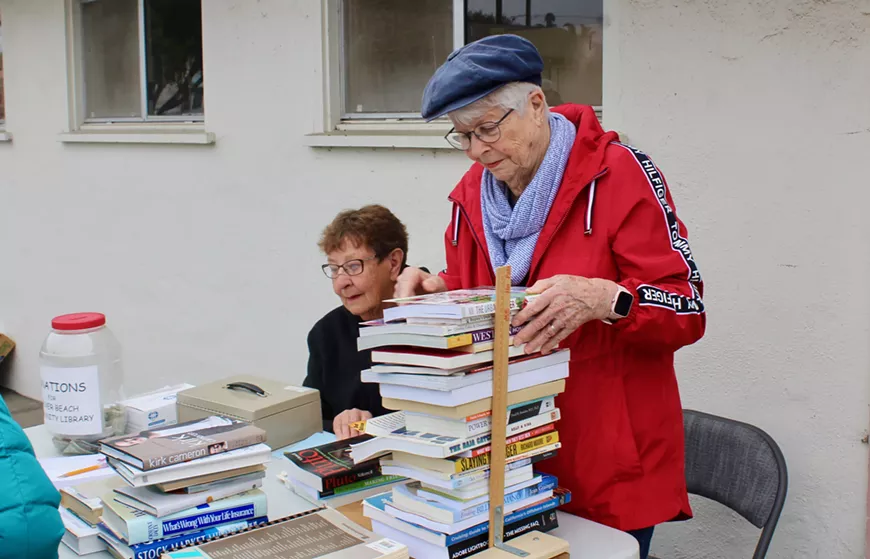 Librarians at Grover Beach Community Library sell a stack of books.