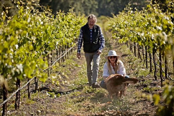 GOOD BOY, ROY Brecon Estate proprietors Damian and Amanda Grindley enjoy a stroll with their friendly 10-year-old companion, Roy, an Australian shepherd-border collie mix who greets customers at their Paso tasting room. - COURTESY PHOTO BY ADAM ROUSE