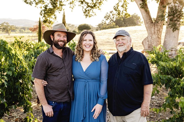FAMILY IS EVERYTHING "There is something beautiful about being surrounded by people you love when you're at work," says Bella Luna General Manager Nichole Healey-Finn, center. Her father, Kevin Healey, right, co-founder of the winery, oversees the vineyard, while her husband, Lukas Finn, left, is head winemaker. - COURTESY PHOTO BY AMY HINRICHS PHOTOGRAPHY