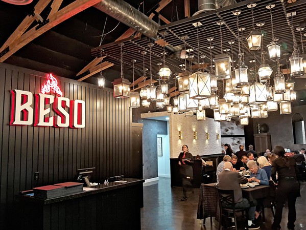LOFTY INTERIOR Beso Cocina is quickly becoming known for its glowing red flame symbol and dark interior set off by a constellation of black wrought iron lamps hanging from the ceiling. - PHOTOS BY BULBUL RAJAGOPAL
