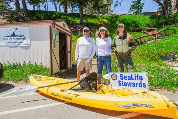 LONGTIME LOYALISTS SeaLife Stewards volunteers Gary Messerotes and Kelley Meece and California State Parks Interpreter Robin Hazard stand with one of the program’s kayaks stored in the shed by the marina launch location. - PHOTO BY JAYSON MELLOM