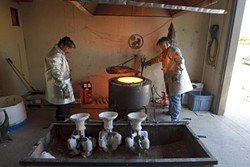 Alphonso Sepeda, left, and John Kemple, right, prepare to pull out the crucible containing the molten bronze. - PHOTO BY STEVE E. MILLER