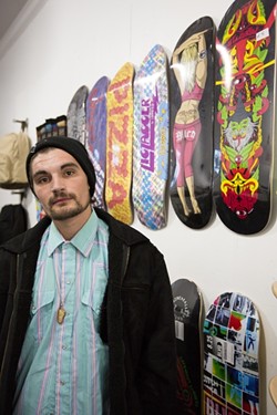 INSPECTAH DECK:  Jake Johnson stands in front of the many custom skateboards at PMA Retail Gallery, where he will be showing his art and neverbefore-seen music video. - PHOTO BY KAORI FUNAHASHI