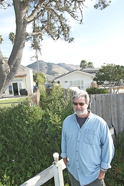 FENCES, NEIGHBORS :  Tim Page of the citizen group Save Our Access Path stands in front of homeowner Mark Yandow&rsquo;s house. The two are working on a settlement to reopen a long-closed path to the beach. - FILE PHOTO