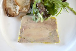 PLATED: :  A slice from a terrine of foie gras is strong enough to be served on its own, accompanied - by greens and a toasted baguette round. - PHOTO BY STEVE E. MILLER