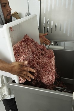 11: :  After grinding, Tesero pours the meat into a mixing machine brought in from Spain.
