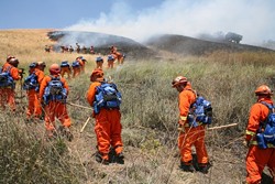 HEAT OF THE MOMENT :  An inmate fire crew, led by California Department of Forestry officers (in the yellow suits), worked to safeguard a burned site from reigniting on Cuesta Grade. - PHOTO BY JESSE ACOSTA