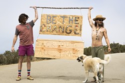 LEAVE NOTHING BUT MEMORIES:  Nate Ross (left) and Logan Leggs (right), of Nomadic Artifacts, hold up a sign made from bottle caps that they collected at Pirate&rsquo;s Cove. - PHOTO COURTESY OF VAGABOND INK.