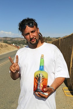 LIGHTNING IN A GIFT :  Mike Dominguez holds up a hand-painted bottle given to him by a woman at LIB. Dominguez believes that LIB is part of the &ldquo;Hopi prophecy of us rebelling against what was created and trying to create something new for the future of our children, for the future of humans.&rdquo; - PHOTO BY DYLAN HONEA-BAUMANN