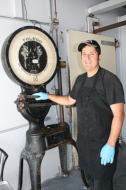 MEAT ACROSS THE AGES:  Rife with history, Arroyo Grande Meat Co. has been a full-service butcher shop since 1897. This scale was used to weigh meat back in the day and&mdash;if owner/butcher Henry Gonzalez (pictured) has his way&mdash;it will one day work again. - PHOTO BY HAYLEY THOMAS CAIN