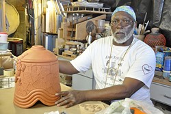 STACK IT UP :  Alonzo Allen Jr. talks about how he creates his ceramic pieces, such as this bell that is waiting for spots of color and glaze. - PHOTO BY CAMILLIA LANHAM