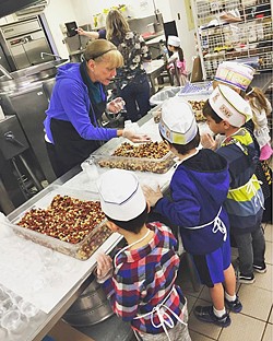 LINING UP San Luis Coastal Unified School District food service worker Jane Nichols demonstrates to first graders how to cup beans for the salad bars at the district's central kitchen. - PHOTO COURTESY OF ERIN PRIMER