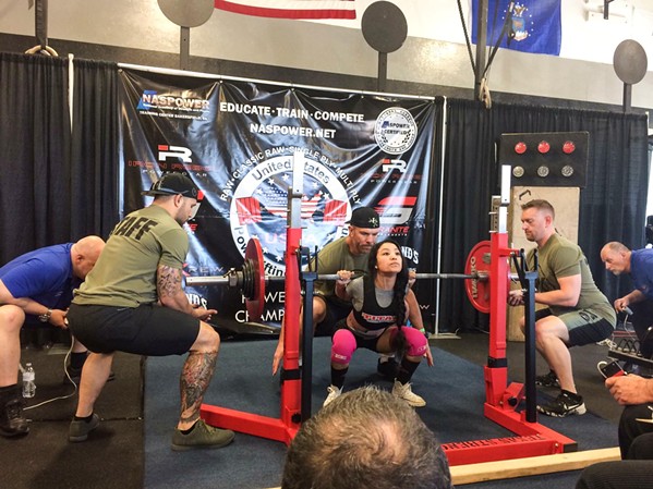 ON HER SHOULDERS Denise Juarez (97 pounds) goes down for a squat at a competition in Santa Clarita in 2017. Today she holds the world record in the squat for her age and weight class: 231.5 pounds. - PHOTO COURTESY OF DENISE JUAREZ