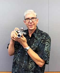 THE MAN BEHIND THE CAMERA Steve Udell poses with one of the cameras he used for his photos in the exhibit at Atascadero Library. - PHOTO BY MALEA MARTIN
