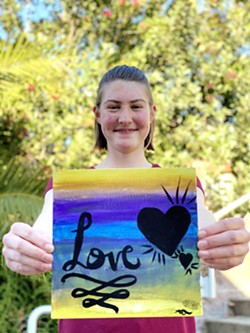 LOVE Aunica Todd, a student at Heartland Charter School, holds up artwork she created for Youth Art After Dark, an exhibit highlighting teen dating violence and healthy relationships. - PHOTO COURTESY OF ARTI KOTHARI ALLARD