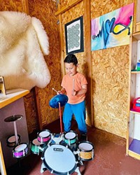 MAKING MUSIC A young Exploration Discovery Center patron makes some tunes in the Music Shed.