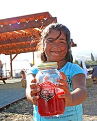FIELD DAY Six-year-old Giuliana Dorado of Julia's Juices celebrates harvest at a rare public City Farm SLO event earlier this month. Behind her, a recently completed pergola offers wind protection for events to come.