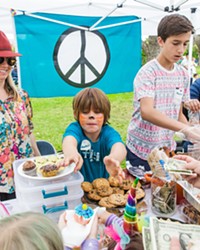 BAKE FOR A CAUSE Ryder Heenan (center), 6, his mother Kristen Heenan (left), and Nathan Durant (right), 14, sell homemade goodies in the Kids for Kids event on June 24 in Mitchell Park. The bake sale raised more than $3,300 for immigrant families who have been separated at the U.S. border.